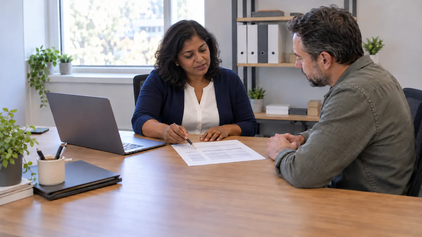 An accountant going over a document with a client across a desk in a bright office